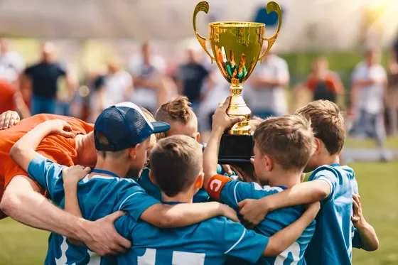 kids in soccer uniform huddled holding up trophey